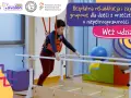 Chłopiec w kamizelce terapeutycznej ćwiczy na poręczach rehabilitacyjnych.