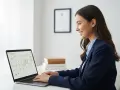 Uśmiechnięta kobieta w garniturze pracuje przy laptopie z kalendarzem urlopów.