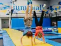 Dzieci robią stanie na rękach na trampolinach w sali gimnastycznej.