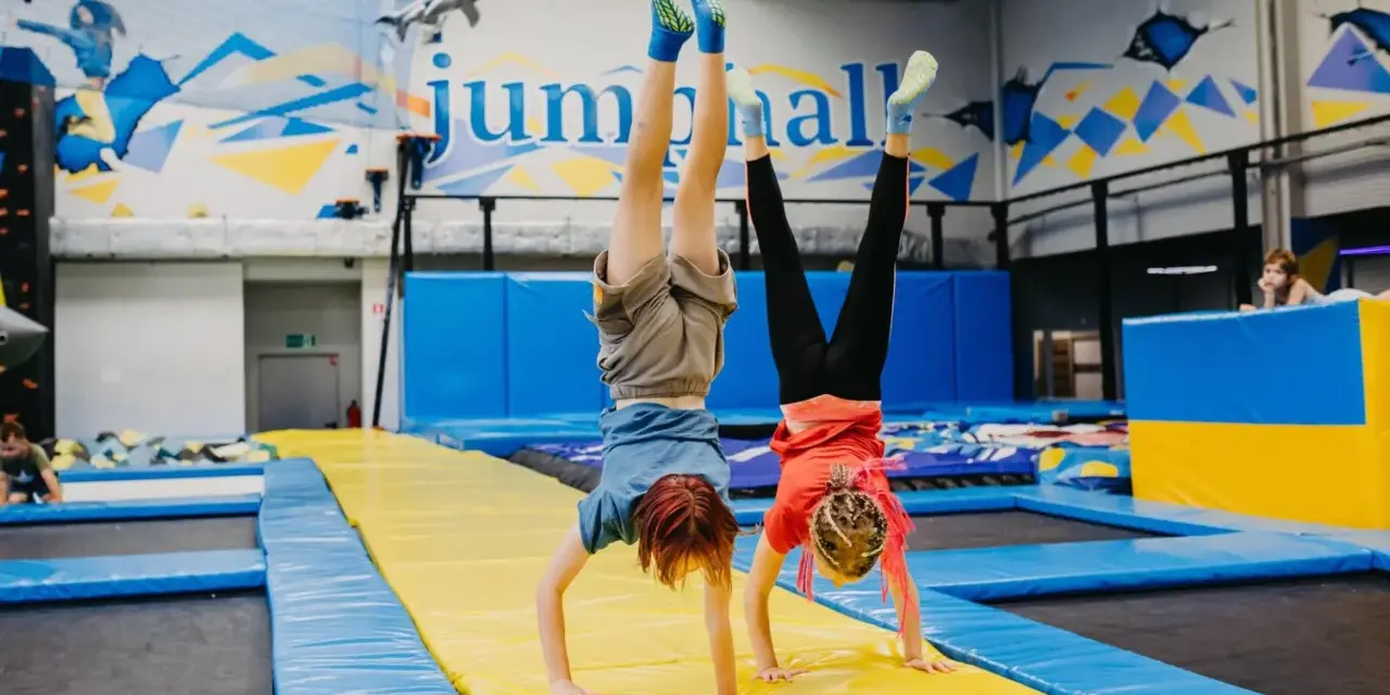 Dzieci robią stanie na rękach na trampolinach w sali gimnastycznej.
