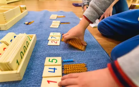 Dzieci bawią się koralikami i kartami z cyframi, ucząc się matematyki.