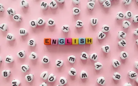 Kolorowe koraliki z literami tworzą napis "ENGLISH" na różowym tle.