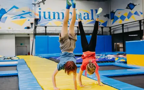 Dzieci robią stanie na rękach na trampolinach w sali gimnastycznej.