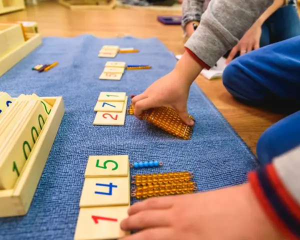 Dzieci bawią się koralikami i kartami z cyframi, ucząc się matematyki.