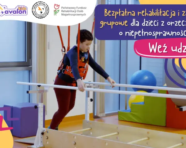 Chłopiec w kamizelce terapeutycznej ćwiczy na poręczach rehabilitacyjnych.