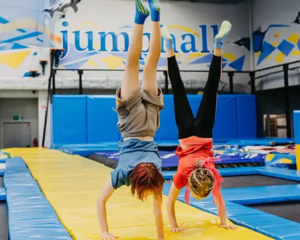 Dzieci robią stanie na rękach na trampolinach w sali gimnastycznej.